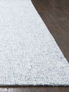 a white rug is laying on the floor in front of a wood flooring area