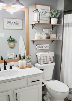 a white toilet sitting next to a sink in a bathroom under two wooden shelves above it