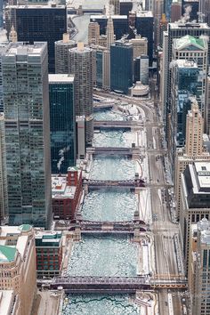 an aerial view of a city with water and bridges in the foreground, surrounded by tall buildings