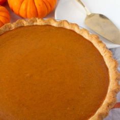 a pumpkin pie sitting on top of a table next to some oranges and a spoon