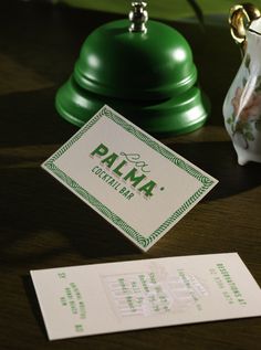 a close up of a business card on a table next to a teapot and paper