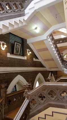 an ornate staircase in the middle of a building with pictures on the wall and windows above it