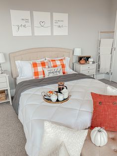 a white bed with orange and gray pillows