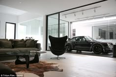 a living room filled with furniture and a car parked in front of the glass doors