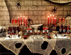 a table topped with lots of candles and skulls on top of white plates covered in spider webs