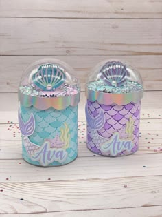 two little mermaid themed jars sitting on top of a wooden table