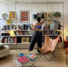 a woman standing on top of a chair in front of a book shelf filled with books