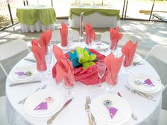 the table is set with pink napkins and silverware