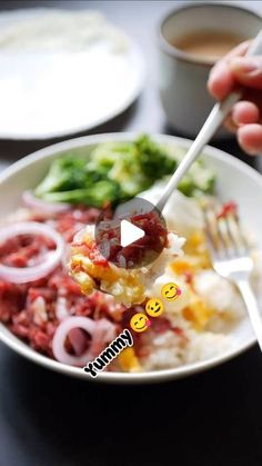 a person holding a fork over a plate of food with broccoli and onions