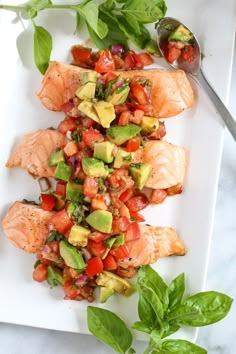 salmon and avocado salad on a white plate with a spoon next to it