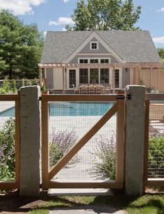 an open gate leading to a house with a pool in the background