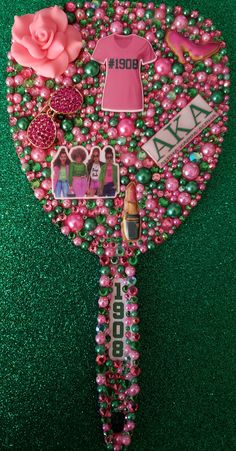 a pink and green brooch with some pictures on the front, along with other items