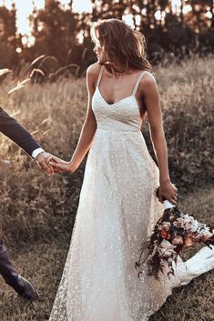 a couple holding hands and walking through the grass in front of an instagram sign