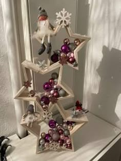 a christmas tree made out of wooden stars and ornaments on top of a white table