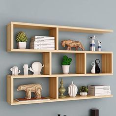 three wooden shelves on the wall with books, vases and figurines in them