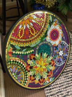 a colorful glass plate sitting on top of a rug next to a chair and christmas tree