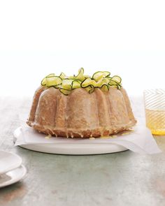 a bundt cake with cucumbers on top sits on a white platter