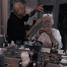 an elderly man and woman taking a selfie in front of a mirror