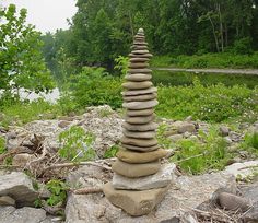 a stack of rocks sitting on top of a rocky ground next to a river and forest