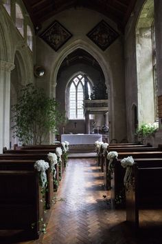 the interior of an old church with pews and flowers on the alter, looking towards the altar