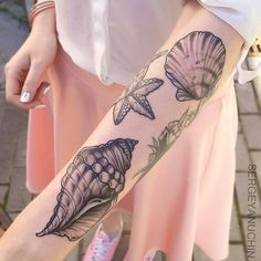 a woman's arm with seashells and flowers tattoo on her left forearm