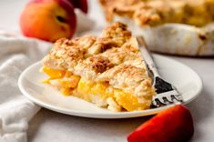 a piece of pie on a white plate next to an apple and another dessert item