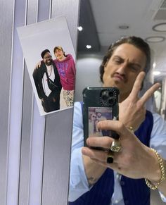 a man taking a selfie with his cell phone in front of him and an image of himself on the mirror