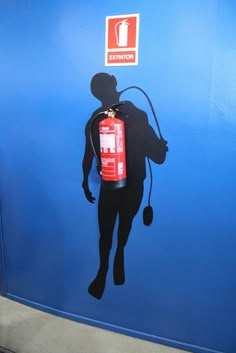 a fire extinguisher is silhouetted against a blue wall with a red and white sign