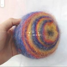 a hand holding a colorful ball of yarn