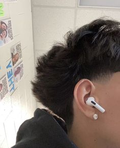 a man with ear buds on his ears in front of a wall covered with stickers