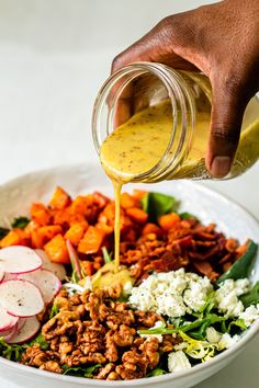 a person pouring dressing over a salad in a bowl