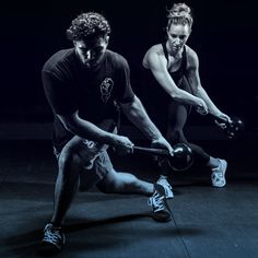 two men are doing exercises with dumbbells in the dark