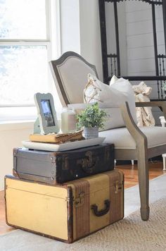 three suitcases stacked on top of each other in front of a chair and window