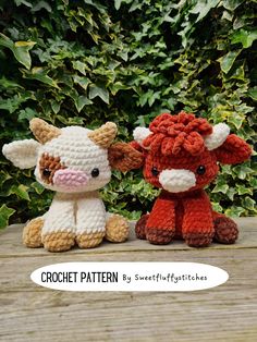 two crocheted stuffed animals sitting next to each other on a wooden table with bushes in the background