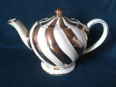 a white and brown striped tea pot on a blue background