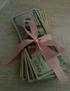 money tied up with a pink ribbon on top of a table