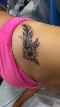 a woman's arm with a tattoo on it that has a feather and flowers