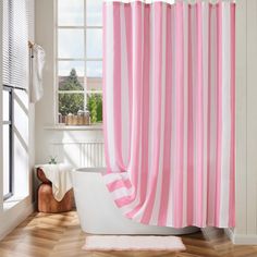 a pink and white striped shower curtain in a bathroom with wood flooring next to a bathtub