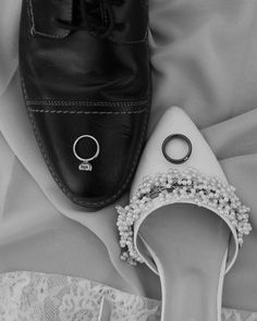 two pairs of shoes with wedding rings on them next to a pair of bridal shoes