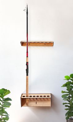 a wooden shelf with a fishing rod on it and a plant in the corner next to it