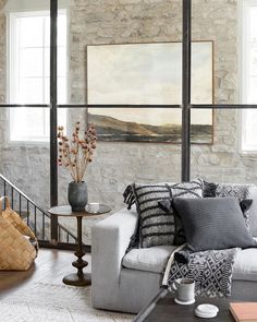 a living room filled with lots of furniture next to a stone wall covered in windows