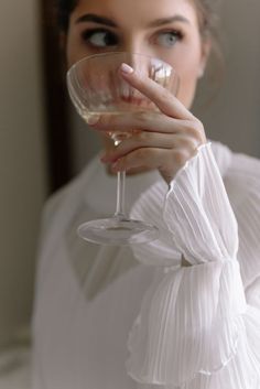 a woman holding a wine glass up to her face