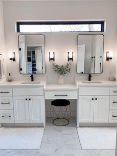 a white bathroom with two sinks and mirrors