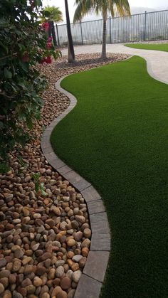 an artificial lawn with rocks and grass in the foreground, next to a palm tree