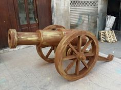 an old wooden cannon sitting on the ground in front of a building with shutters