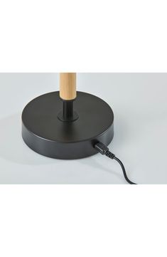 a black table lamp with a wooden stick on it's base and an electric cord plugged in