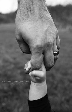 a black and white photo of a person holding the hand of a child's hand