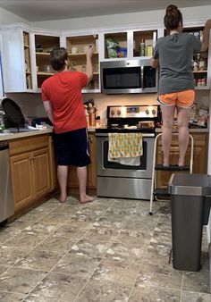 two people standing in a kitchen next to an oven and stove with the door open