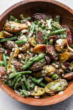 a wooden bowl filled with green beans and potatoes