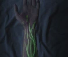 a person's hand with green and yellow streaks on it, in the dark